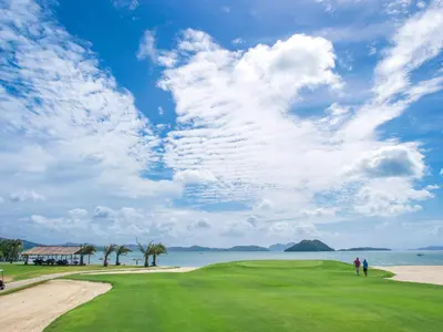 two people standing on a golf course next to the ocean at Mission Hills Phuket Golf Resort-SHA Extra Plus in Por Bay