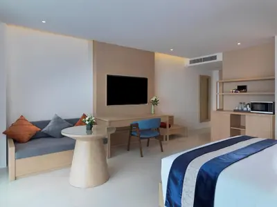 a bedroom with a bed and a couch and a tv at Chanalai Flora Resort, Kata Beach in Kata Beach