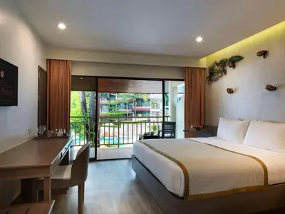 a hotel room with a bed and a desk and a desk at Chanalai Flora Resort, Kata Beach in Kata Beach
