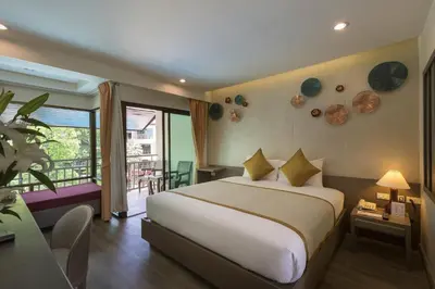 a bedroom with a large bed and a balcony at Chanalai Flora Resort, Kata Beach in Kata Beach