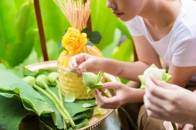 a woman is planting a plant in a basket at Ma Doo Bua Stay - SHA Extra Plus in Thalang