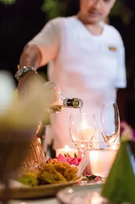 a woman pouring wine into glasses on a table at Ma Doo Bua Stay - SHA Extra Plus in Thalang