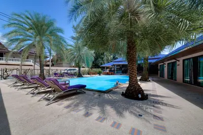 a row of lounge chairs next to a pool with palm trees at MA MAISON BOUTIQUE HOTEL. in PHUKET in Bang Tao Beach