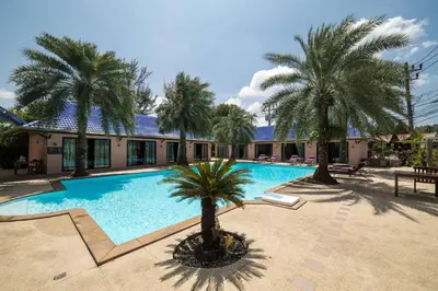 a swimming pool with palm trees in front of a building at MA MAISON BOUTIQUE HOTEL. in PHUKET in Bang Tao Beach