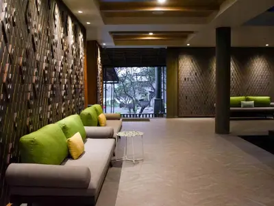 a lobby with a couch with green pillows at Andaman Cannacia Resort & Spa - SHA Extra Plus in Kata Beach