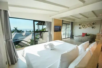 a bedroom with a white bed and a large window at Andaman Cannacia Resort & Spa - SHA Extra Plus in Kata Beach