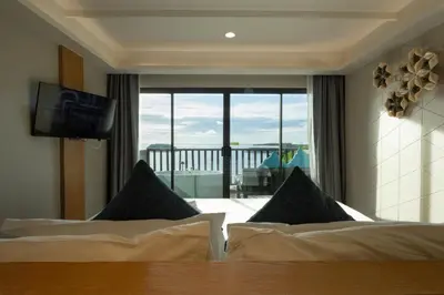 a bedroom with two beds and a view of a balcony at Andaman Cannacia Resort & Spa - SHA Extra Plus in Kata Beach