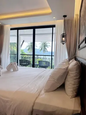 a bedroom with a large bed with a view of the ocean at Peach Hill Resort - SHA Extra Plus in Kata Beach