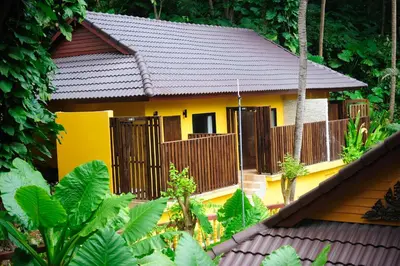 a yellow house with a fence in front of it at Peach Hill Resort - SHA Extra Plus in Kata Beach