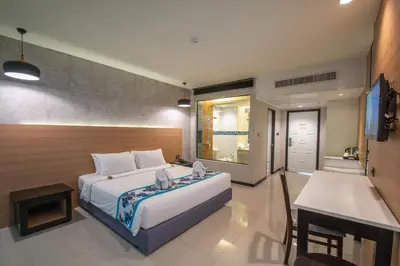 a bedroom with a bed and a desk and a television at Peach Hill Resort - SHA Extra Plus in Kata Beach