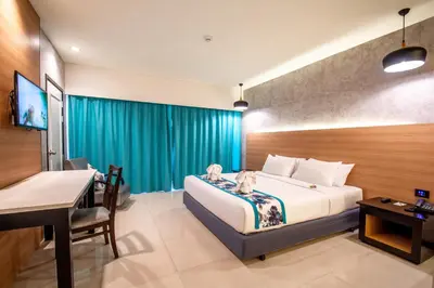 a bedroom with a bed and a desk and a television at Peach Hill Resort - SHA Extra Plus in Kata Beach