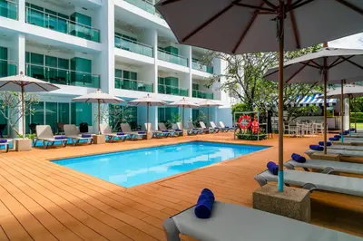 a swimming pool with chairs and umbrellas in a hotel at The Old Phuket - Karon Beach Resort in Karon Beach