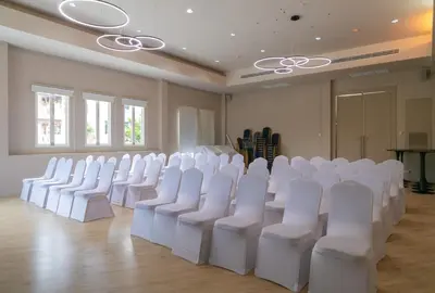 an empty room with white chairs and a table at The Old Phuket - Karon Beach Resort in Karon Beach