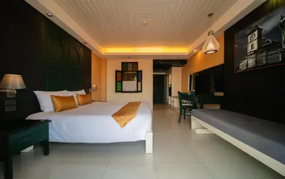 a hotel room with a bed and a couch at The Old Phuket - Karon Beach Resort in Karon Beach