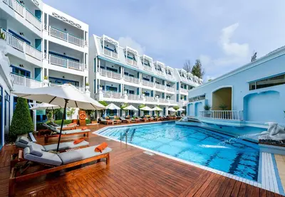 a pool with chairs and umbrellas in a hotel at Andaman Seaview, Karon Beach - SHA Plus in Karon Beach