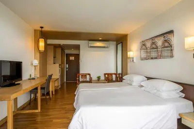 a hotel room with two beds and a desk and a television at Best Western Phuket Ocean Resort in Karon Beach