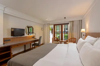 a hotel room with a bed and a desk and a television at Sunprime Kamala Beach in Kamala Beach