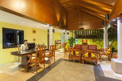 a man sitting at a table with a computer in a room at By The Sea in Panwa Beach
