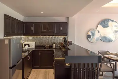 a kitchen with brown cabinets and a black counter top at The Pe La Resort, Phuket - SHA Extra Plus in Kamala Beach