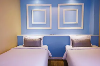 two beds in a blue room with two windows at The Beach Boutique House in Kata Beach