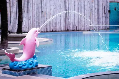 a pink dolphin statue in front of a swimming pool at The Beach Boutique House in Kata Beach