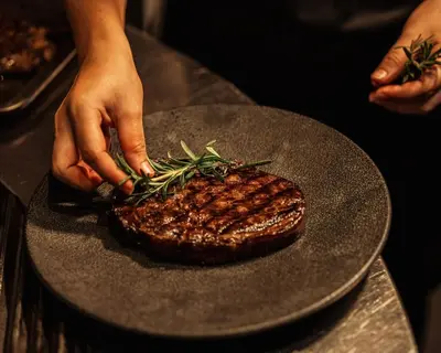 a person is preparing a steak on a plate at Twinpalms Surin Beach Phuket in Surin Beach