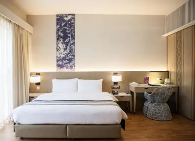 a bedroom with a bed and a desk with a chair at The Royal Paradise Hotel & Spa in Patong Beach