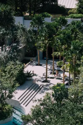 a courtyard with palm trees and people sitting on benches at The Royal Paradise Hotel & Spa in Patong Beach