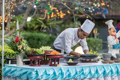 a chef preparing food on top of a table at Diamond Cottage Resort & Spa in Karon Beach