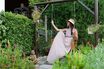 a woman sitting on a swing in a garden at Diamond Cottage Resort & Spa in Karon Beach