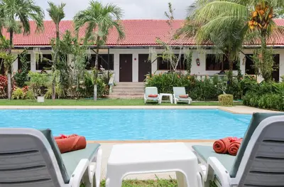 a swimming pool with lounge chairs and a house at The Golddiggers Resort in Nai Yang Beach