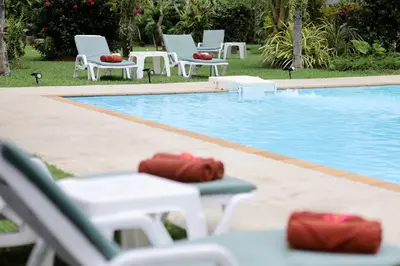 a group of white chairs and a swimming pool at The Golddiggers Resort in Nai Yang Beach