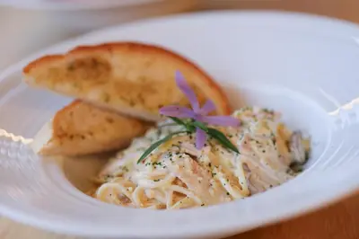 a white plate of food with pasta and bread at The Golddiggers Resort in Nai Yang Beach
