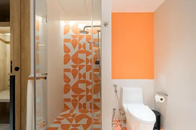 an orange bathroom with a toilet and a shower at Centara Karon Resort Phuket in Karon Beach