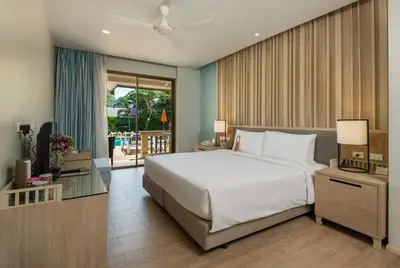 a bedroom with a large white bed and a balcony at Centara Kata Resort Phuket in Kata Beach