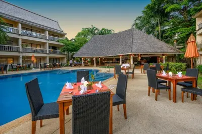 a restaurant with tables and chairs next to a swimming pool at Centara Kata Resort Phuket in Kata Beach