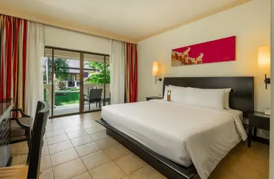 a bedroom with a large white bed and a desk at Centara Kata Resort Phuket in Kata Beach