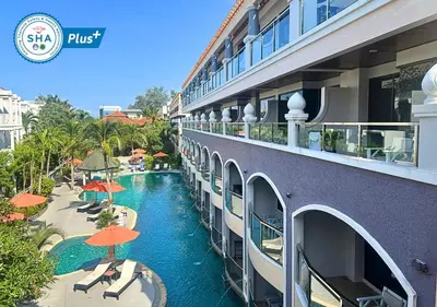 a hotel with a swimming pool and orange umbrellas at Karon Sea Sands Resort-SHA PLUS in Karon Beach