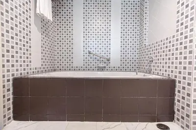 a bath tub in a bathroom with black and white tiles at Karon Sea Sands Resort-SHA PLUS in Karon Beach