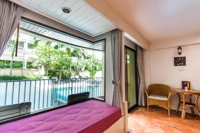 a room with a balcony with a bed and a window at Karon Sea Sands Resort-SHA PLUS in Karon Beach