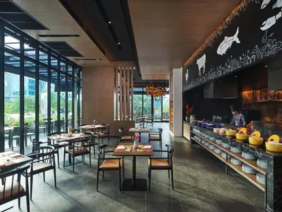 a restaurant with tables and chairs and a chef in the background at Holiday Inn Resort Krabi Ao Nang Beach by IHG in Ao Nang Beach