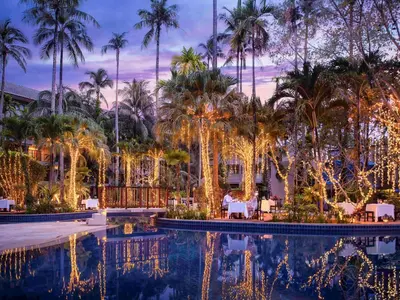 a resort pool with christmas lights and palm trees at Holiday Inn Resort Phuket Surin Beach by IHG in Surin Beach