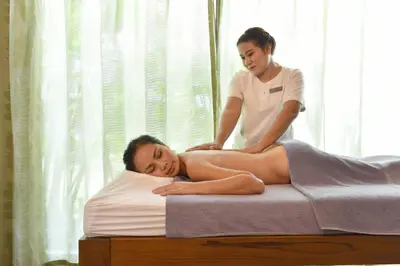 a woman laying on a bed with a woman getting acupuncture at Holiday Inn Resort Phuket Surin Beach by IHG in Surin Beach