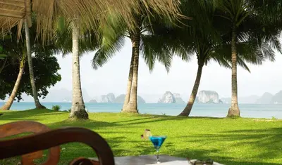 a table with a blue drink sitting on top of the grass at Koyao Island Resort in Ko Yao Noi