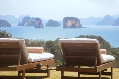 two chairs sitting next to the ocean with rocks in the background at Koyao Island Resort in Ko Yao Noi