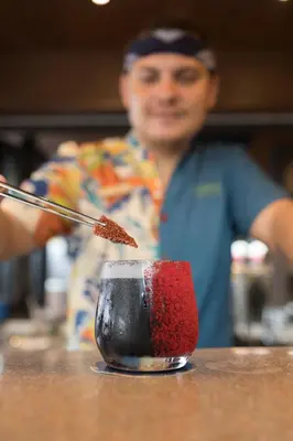 a man sitting at a table with a red and black drink at Barcelo Coconut Island, Phuket in Phuket Town