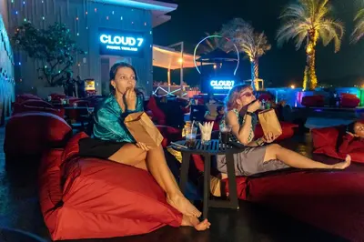 two women sitting on bean bags at a restaurant at night at Radisson RED Phuket Patong Beach in Patong Beach