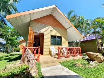a small yellow house with a porch and a chair at Mild Garden View Resort in Ao Nang Beach