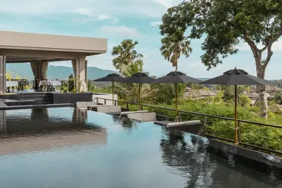 a swimming pool with umbrellas and chairs next to a resort at The Pavilions Phuket in Bang Tao Beach