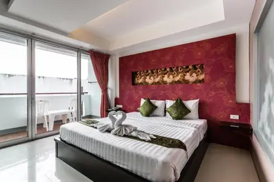 a bedroom with a large bed with a red wall at 7Q Patong Beach Hotel in Patong Beach